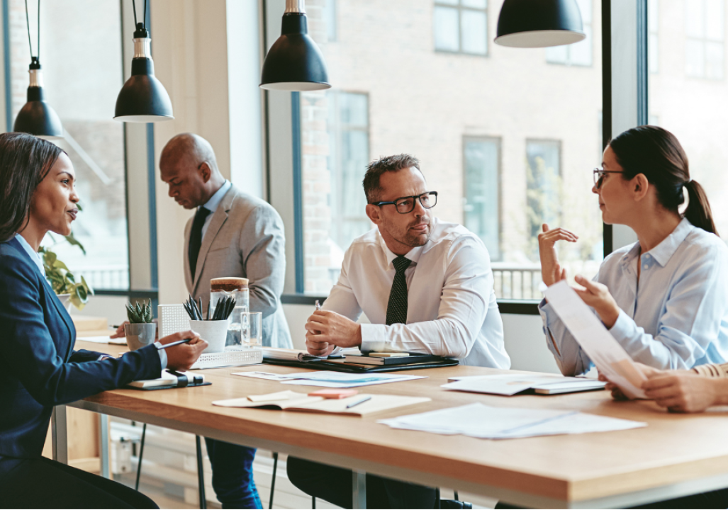 Group of businesspeople talking together around an office table
