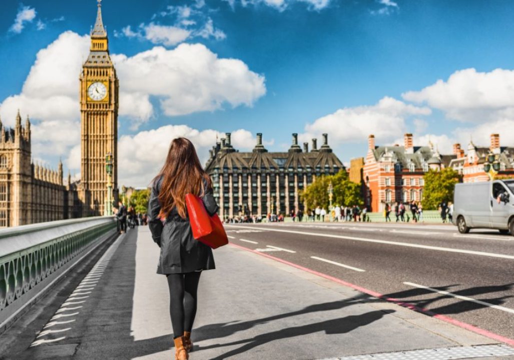 London city urban lifestyle tourist woman walking. Businesswoman commuting going to work on Westminster bridge street early morning. Europe travel destination, England, Great Britain, UK.