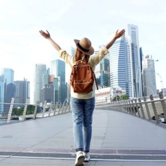 Young woman traveler with backpack and hat traveling into Singapore city downtown. Travelling in Singapore concept.