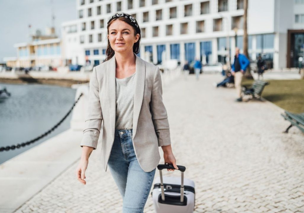 Young woman with a suitcase walking in urban settings.