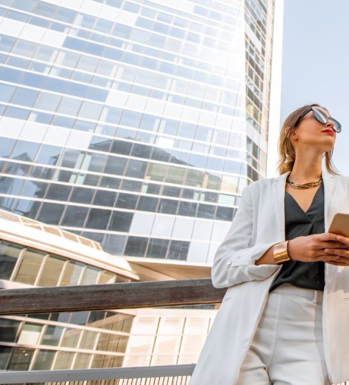 Woman standing with a mobile phone surrounded by tall buildings.