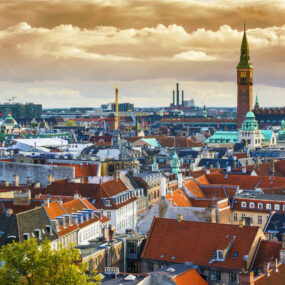 overhead view of Copenhagen, Denmark with red tiled roofs and City Hall clock tower in the background.