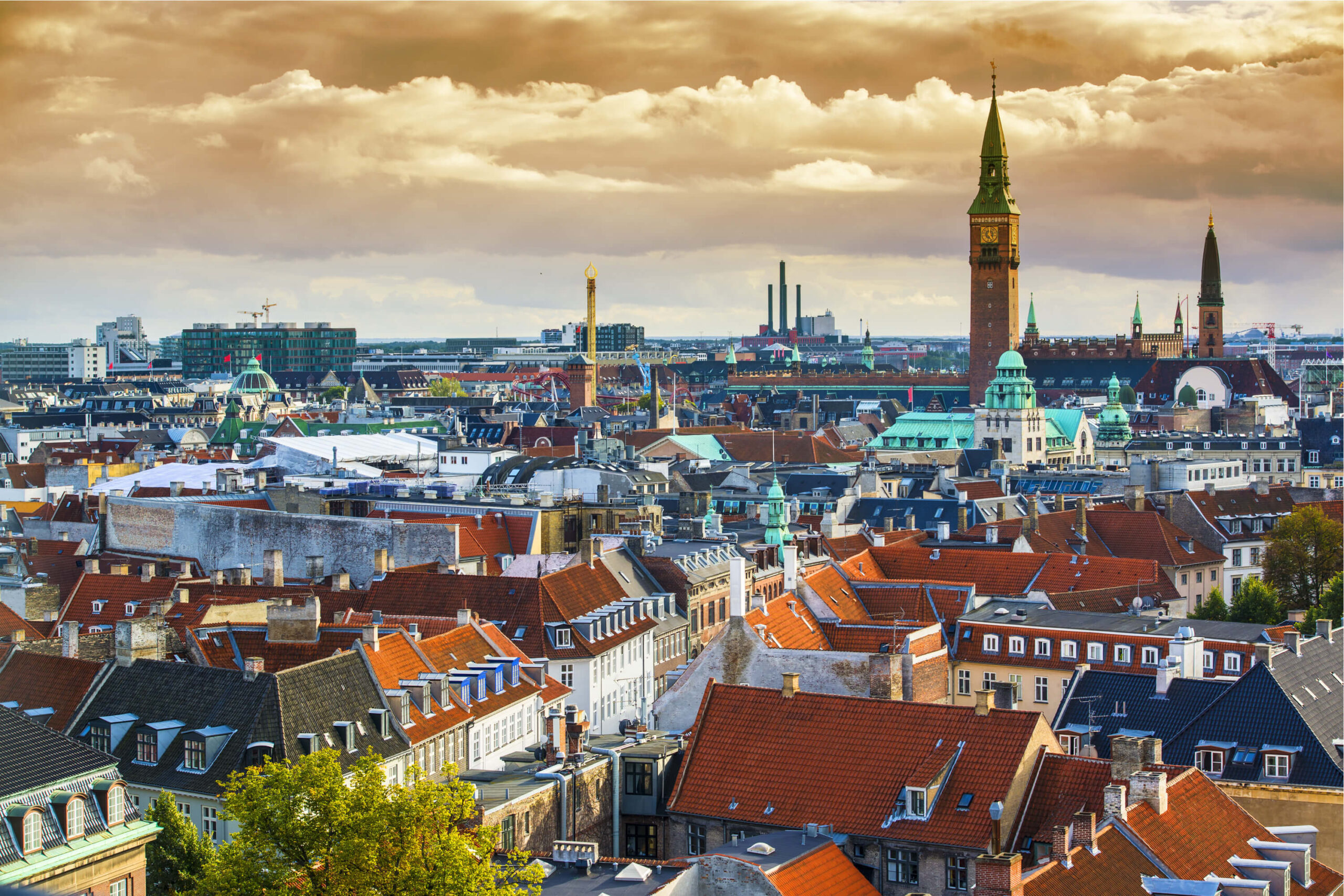 overhead view of Copenhagen, Denmark with red tiled roofs and City Hall clock tower in the background.