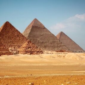 Three pyramids standing prominently in the desert landscape of Egypt on a sunny day.