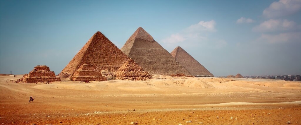Three pyramids standing prominently in the desert landscape of Egypt on a sunny day.