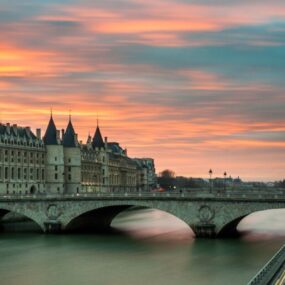 A bridge over the Seine River in Paris, France during sunset or sunrise.