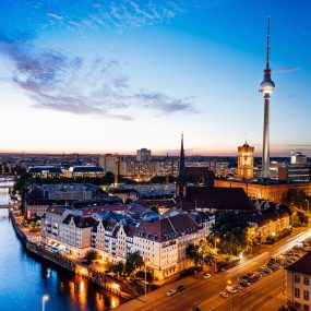 Fernsehturm in Berlin, Germany prominently in the skyline, along with the Spree River at night.