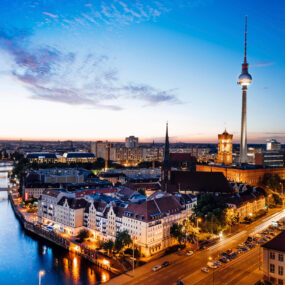 Fernsehturm in Berlin, Germany prominently in the skyline, along with the Spree River at night.