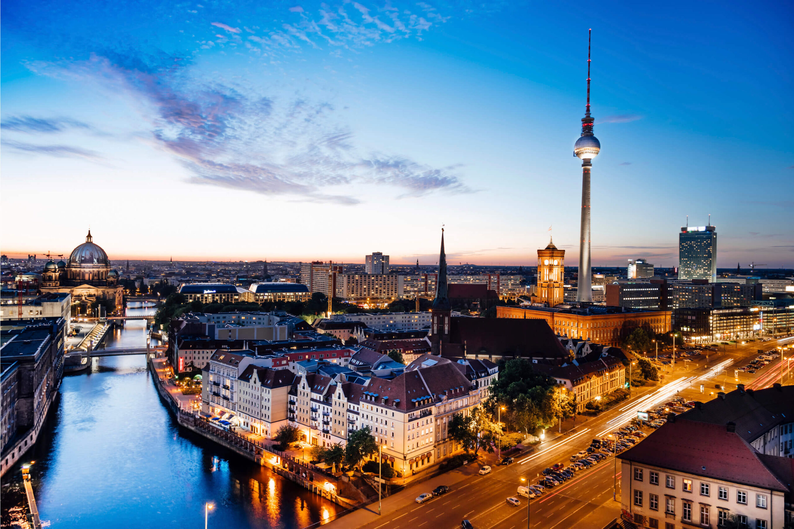 Fernsehturm in Berlin, Germany prominently in the skyline, along with the Spree River at night.