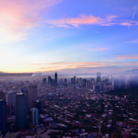 A panoramic view of Manila, Philippines with numerous high-rise buildings and a hazy sky.
