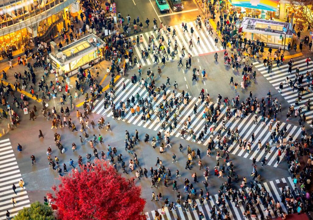 Shibuya Crossing in Tokyo with pedestrians cross from all directions.