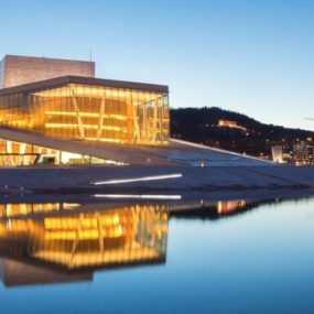 Oslo, Norway, featuring the Oslo Opera House over calm waters, with city lights and hills in the background.