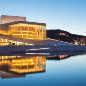 Oslo, Norway, featuring the Oslo Opera House over calm waters, with city lights and hills in the background.