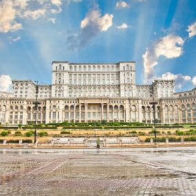 Bucharest, Romania, featuring the Palace of the Parliament under a partly cloudy sky.