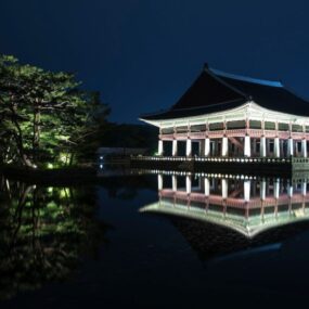 A palace in South Korea displayed in traditional Korean architectural style and reflection in a pond at night.