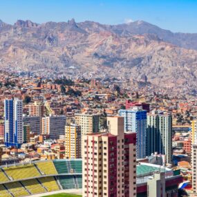 Nuestra Senora de La Paz colorful city town center with skyscrapers, football stadium and lots of living houses scattered on the hills with Andes mountains in background, Bolivia.