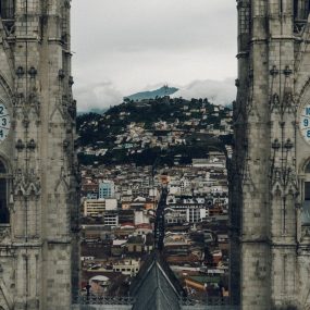 a view between the twin clock towers of the Basilica del Voto Nacional, looking out over the city of Quito, Ecuador.