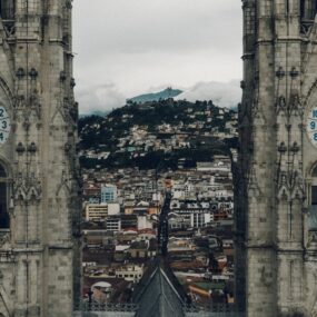 a view between the twin clock towers of the Basilica del Voto Nacional, looking out over the city of Quito, Ecuador.