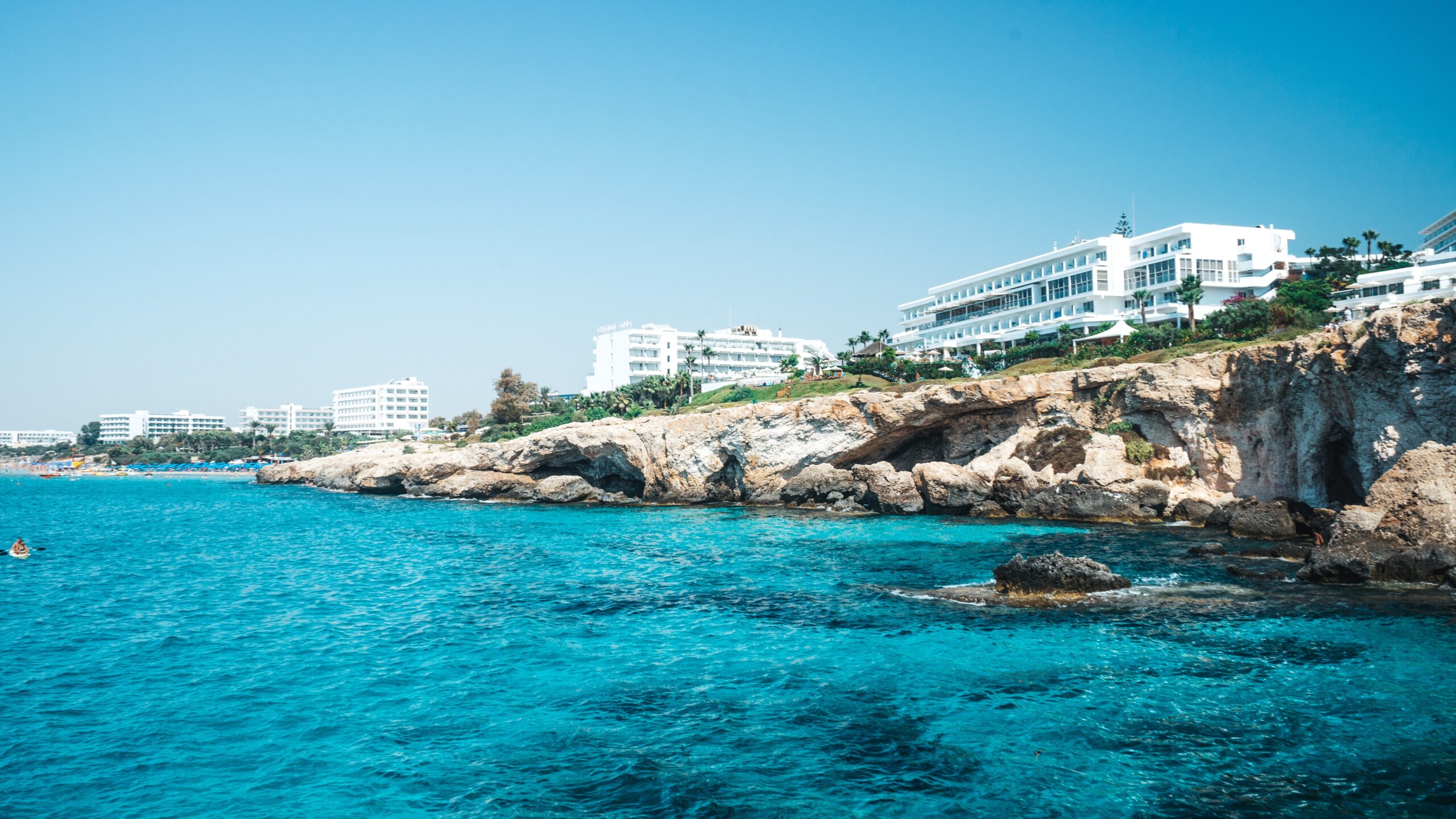 Finland coastline featuring clear turquoise waters, rocky coastlines, and white modern hotel-like buildings.