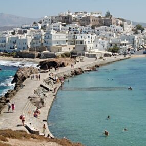Naxos Town on the island of Naxos, Greece featuring distinctive white-washed architecture built on a hill, overlooking the turquoise waters of the Aegean Sea.
