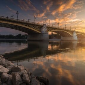 Margaret Bridge in Budapest, Hungary spanning the Danube River, with distinctive yellow color and lampposts during a beautiful sunset.