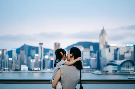 Woman holding a child in front of a city skyline