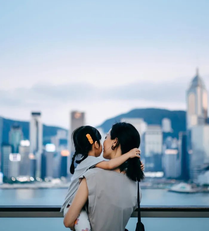 Woman holding a child in front of a city skyline
