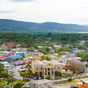 Charming town with colonial-era buildings in Falmouth, Jamaica. Colorful roofs, and lush green hills in the background.