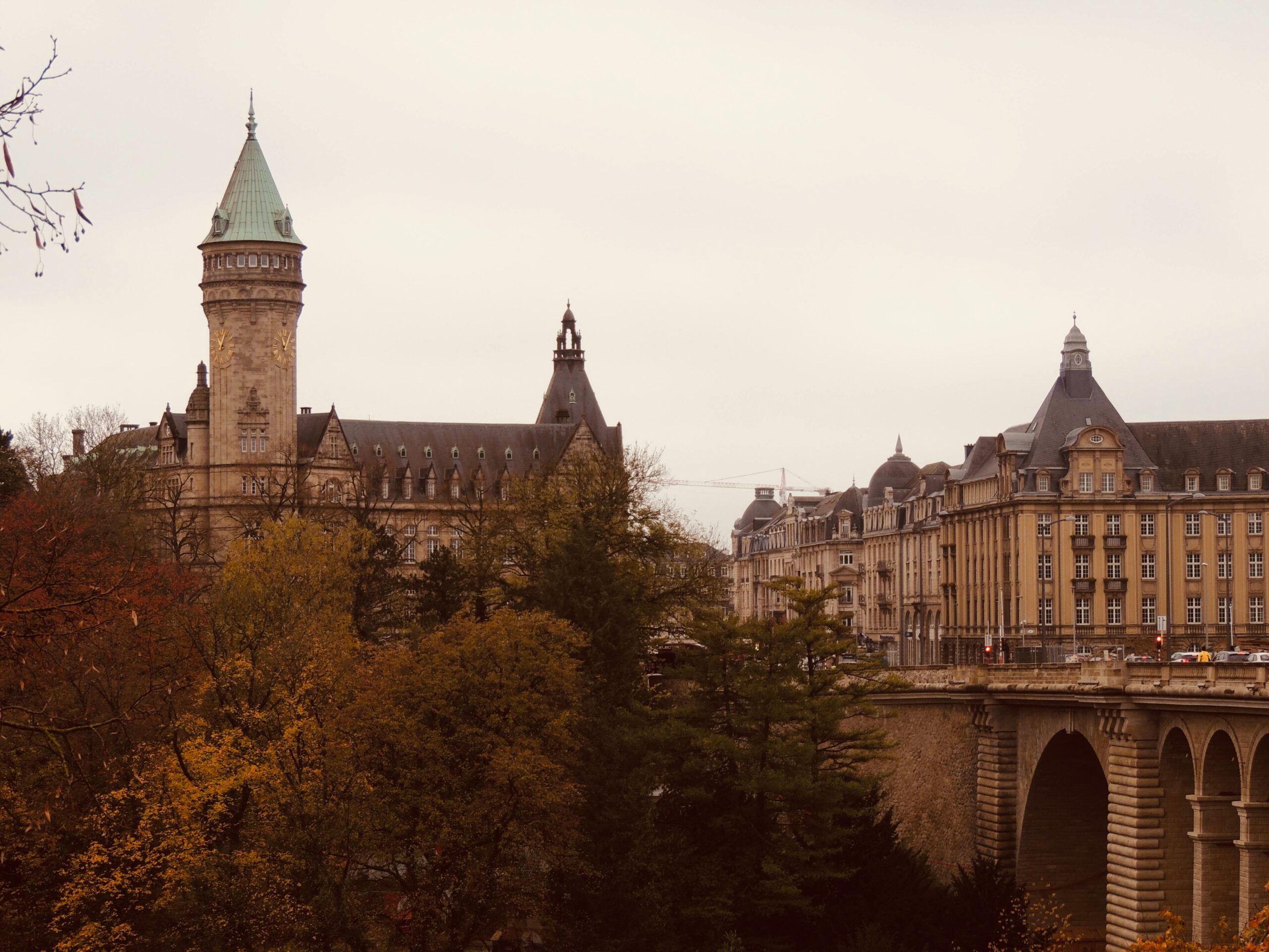 Luxembourg featuring Adolphe Bridge and the surrounding historic buildings and lush autumnal trees in a sepia tone.