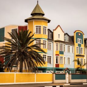 Swakopmund, Namibia, colorful colonial buildings with a palm tree in the foreground.