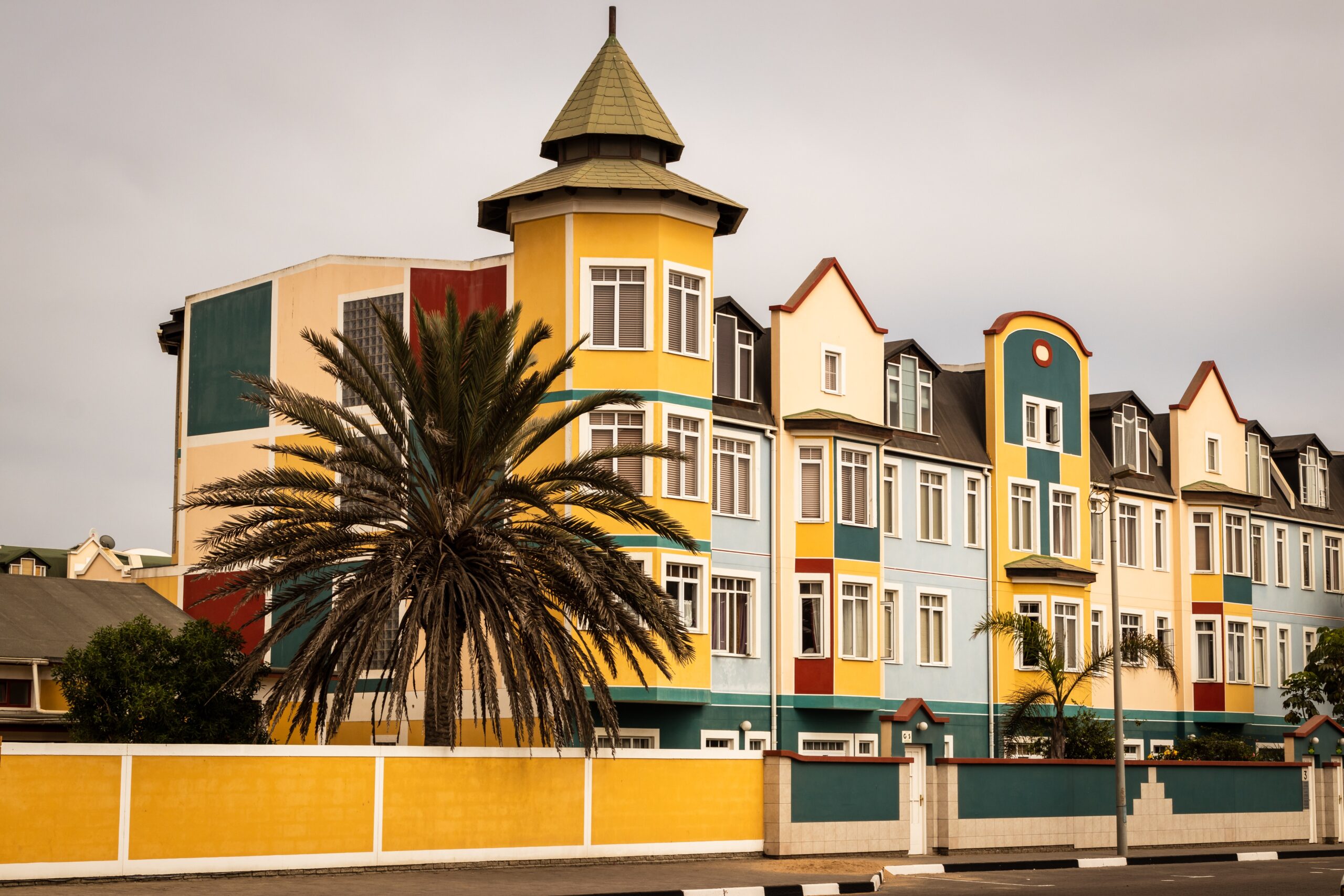 Swakopmund, Namibia, colorful colonial buildings with a palm tree in the foreground.