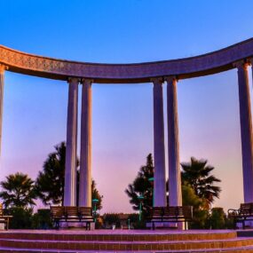 A monument in Pakistan featuring a series of columns arranged in a semi-circle, overlooking a landscaped area.
