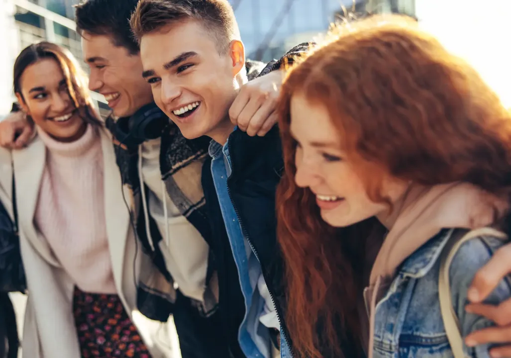 Group of people smiling and enjoying themselves outside in the sunlight.