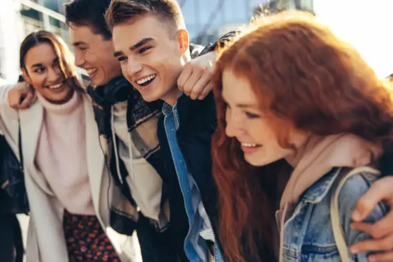 Group of people smiling and enjoying themselves outside in the sunlight.